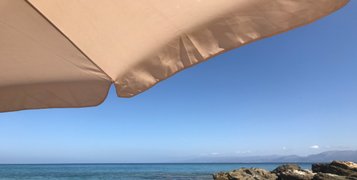 Θέα της θάλασσας και του μπλε ουρανού μπροστά από μία άσπρη ομπρέλα